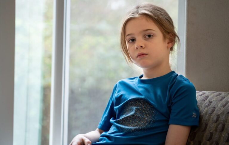 A girl sitting on a chair next to a window