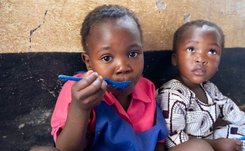 Two children sitting and eating food in Africa