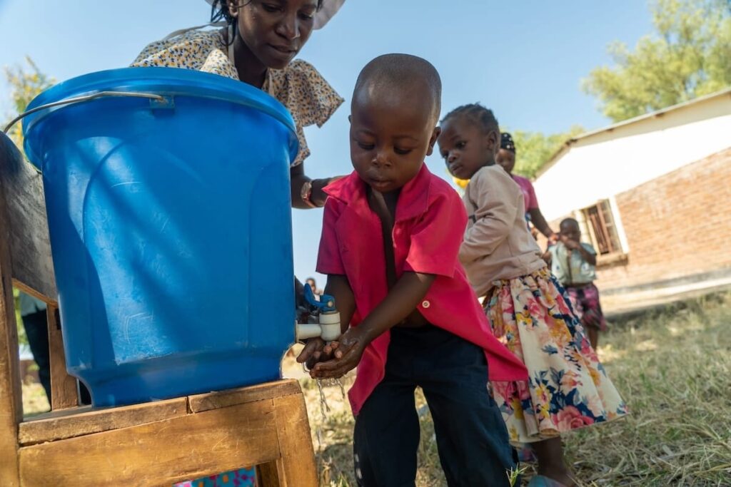 People washing hands with water from a bucket